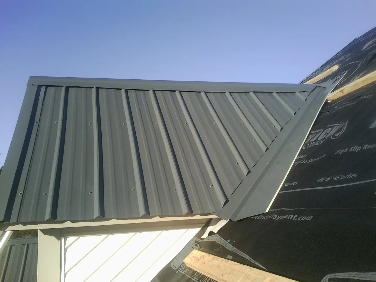 Gray metal roof panels going on over a garage gable in Crestline