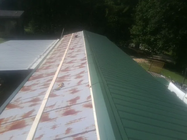 Old rusted panels beside newly installed green metal roofing — Wind Damage Roof Repair by Roofing Brothers in Crestline