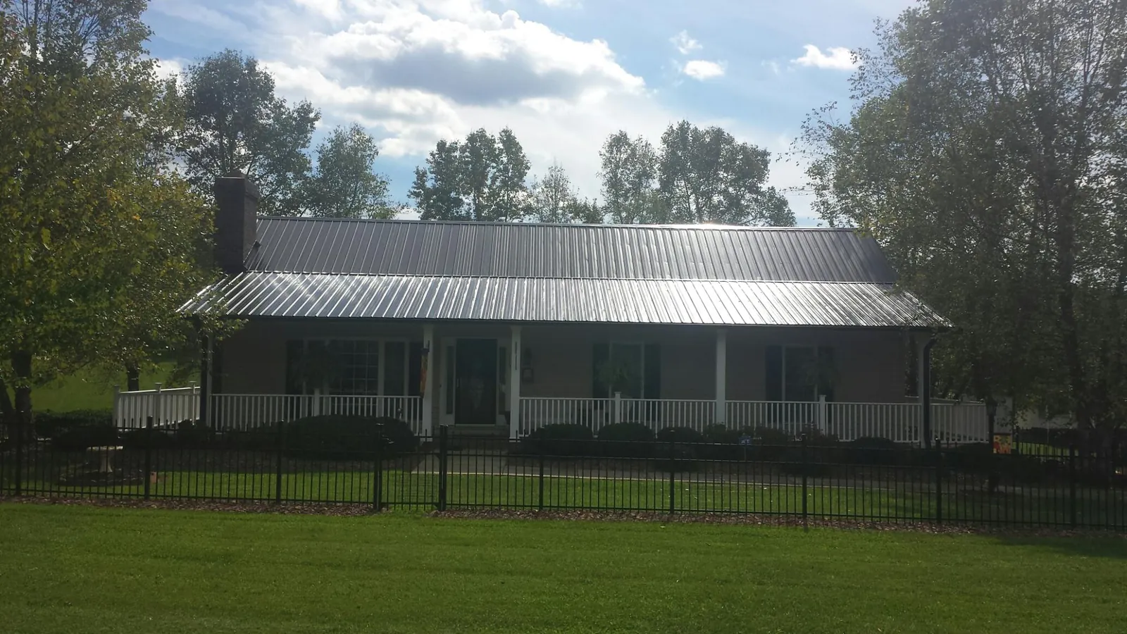 Gray metal roof on a brick ranch with a full width front porch — Gutter Guard Installation work by our crew in Crestline