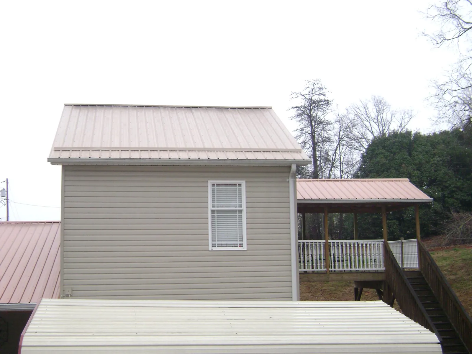 Tan metal roofs on a two story addition and attached porch, from a Roof Replacement job in Crestline